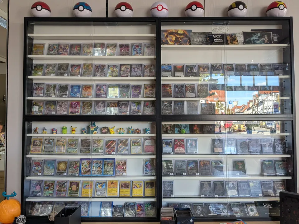 Zwei große Vitrinen mit Pokémon-Sammelkarten und Pokébällen